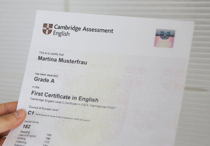 Eine Hand hält das Sprachzertifikat First Certificate in English.